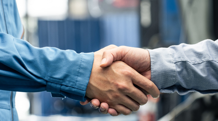 Up close to technician and customer handshake inside garage | American Import Auto